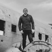 A man stood on a DC-3 aeroplane wreck in Iceland